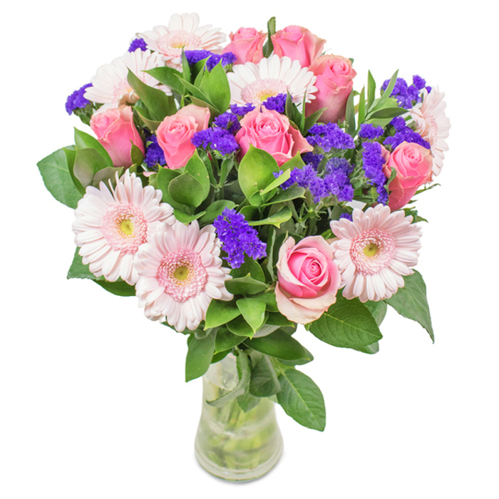 This vibrant, elegantly composed bouquet from Lewisham is presented in a clear glass vase against a pristine backdrop, making each hue and detail pop. Seven to nine classic pink roses, some petals tenderly furled, some modestly opening into signature spirals, form the arrangement's romantic heart. Around them, five to seven pale pink gerbera daisies beckon with their large, lively faces and radiant petals, reminiscent of the cheerful blooms that brighten Lewisham's local parks. Sprays of bright purple statice provide vivid accent and textural interest, echoing the diversity and energy seen at Brockley Market. Lush green foliage cradles the arrangement, hinting at the refreshing abundance of walking through Mountsfield Park or along Ravensbourne River. Naturally displayed in a transparent vase, visible stems immersed in fresh water evoke recent delivery and the hands-on care Lewisham florists bring to their craft. Perfect for occasions like birthdays, anniversaries, or simple moments of shared affection, this bouquet conveys celebration, joy, and a heartfelt connection to the vibrant life of Lewisham.